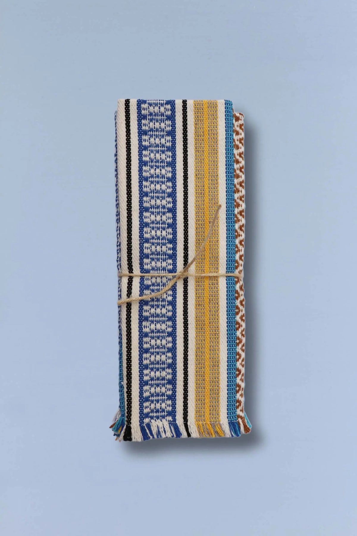 Pack de 2 manteles textiles rectangulares con rayas, motivos geométricos, tonos azules, amarillos y flecos finales.