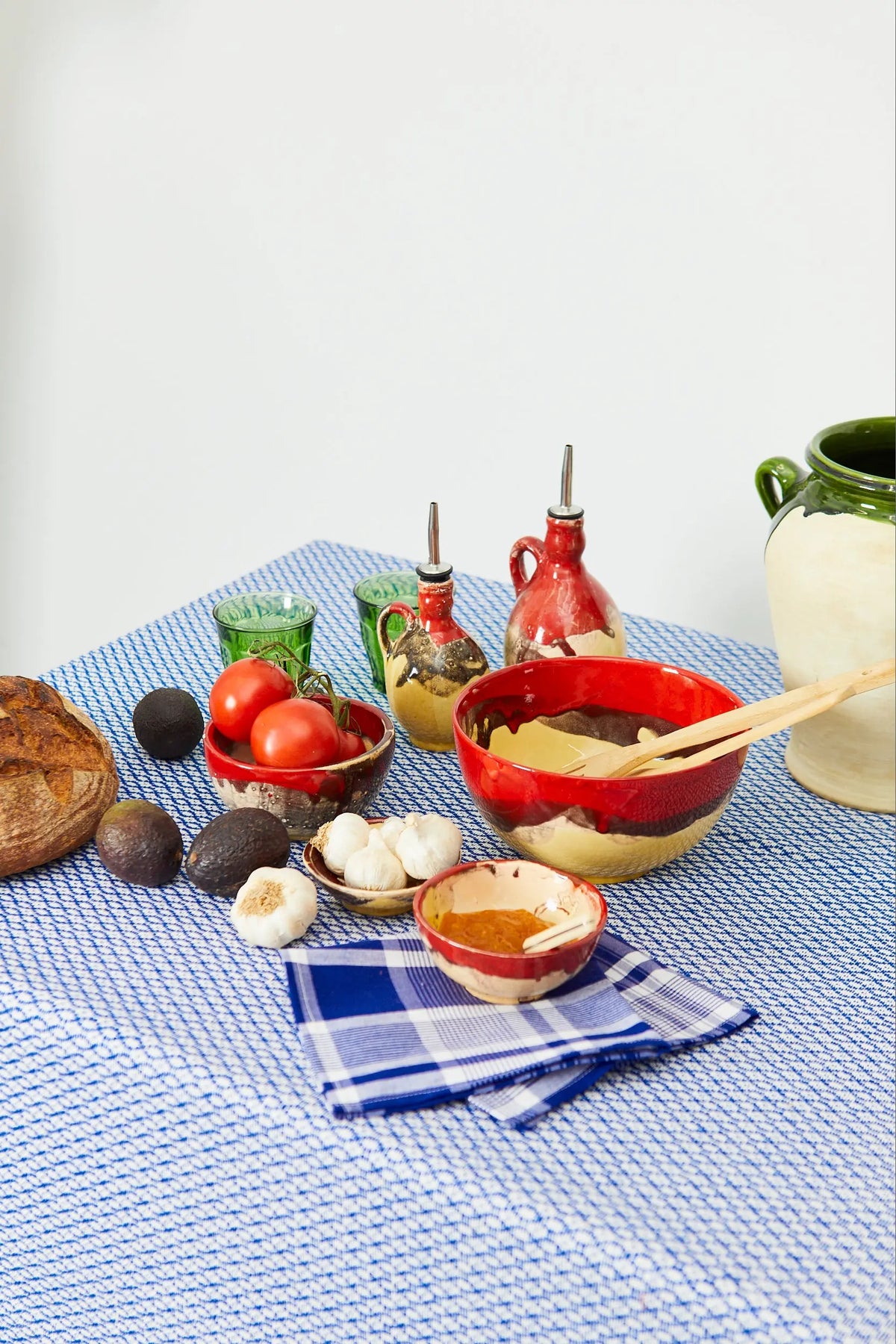 Mantel azul con estampado ojo de perdiz sobre mesa decorada con cuencos artesanales, pan y verduras frescas.