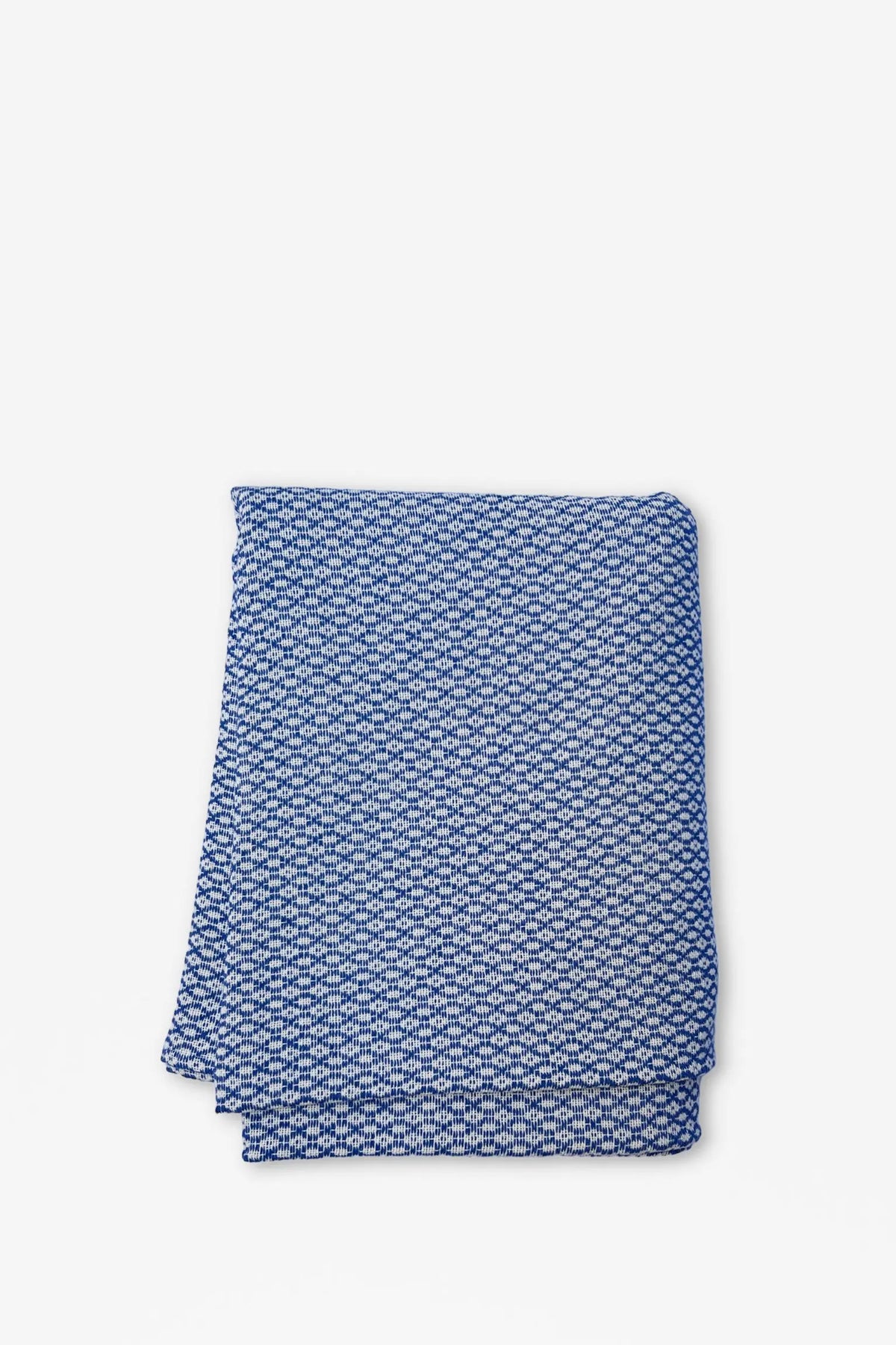 Mantel de tela azul y blanco con estampado geométrico tipo ojo de perdiz doblado sobre fondo blanco.