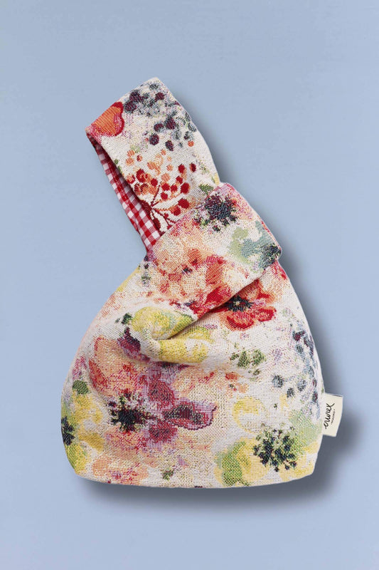 Bolso hatillo mini de tela jacquard con estampado de amapolas coloridas y forro interior de cuadros rojos y blancos.