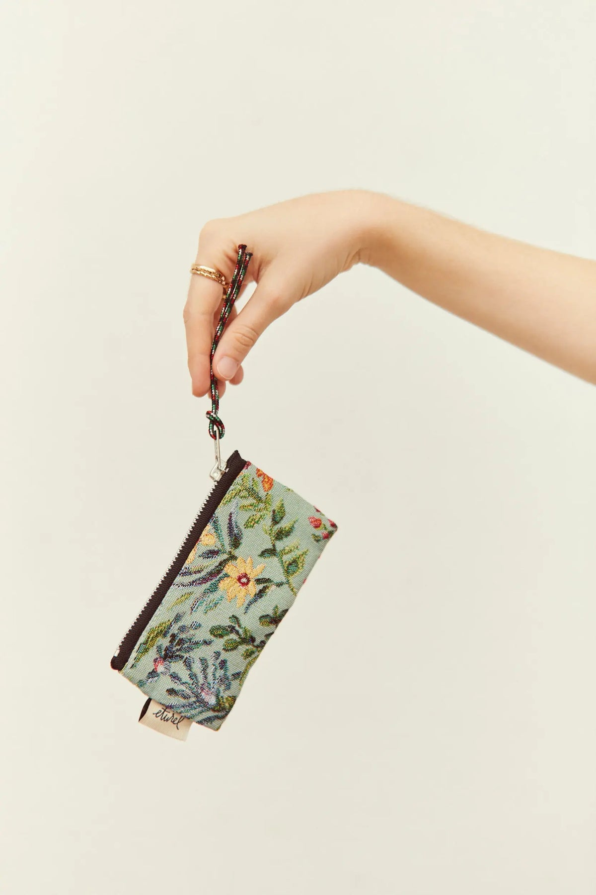 Monedero tejido tipo jacquard con estampado de flores azaleas en tonos celestes, cierre de cremallera y cordón de mano.