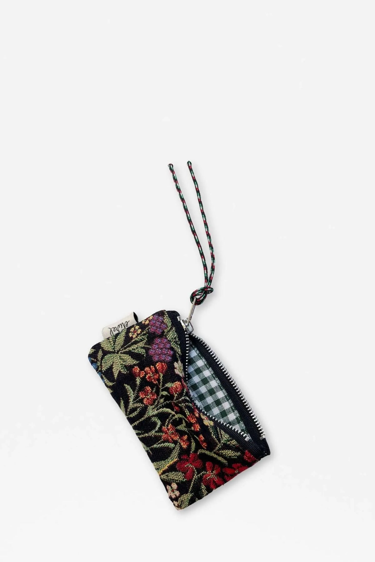 Monedero de tela jacquard con estampado floral sobre fondo negro, cremallera metálica y forro interior a cuadros.