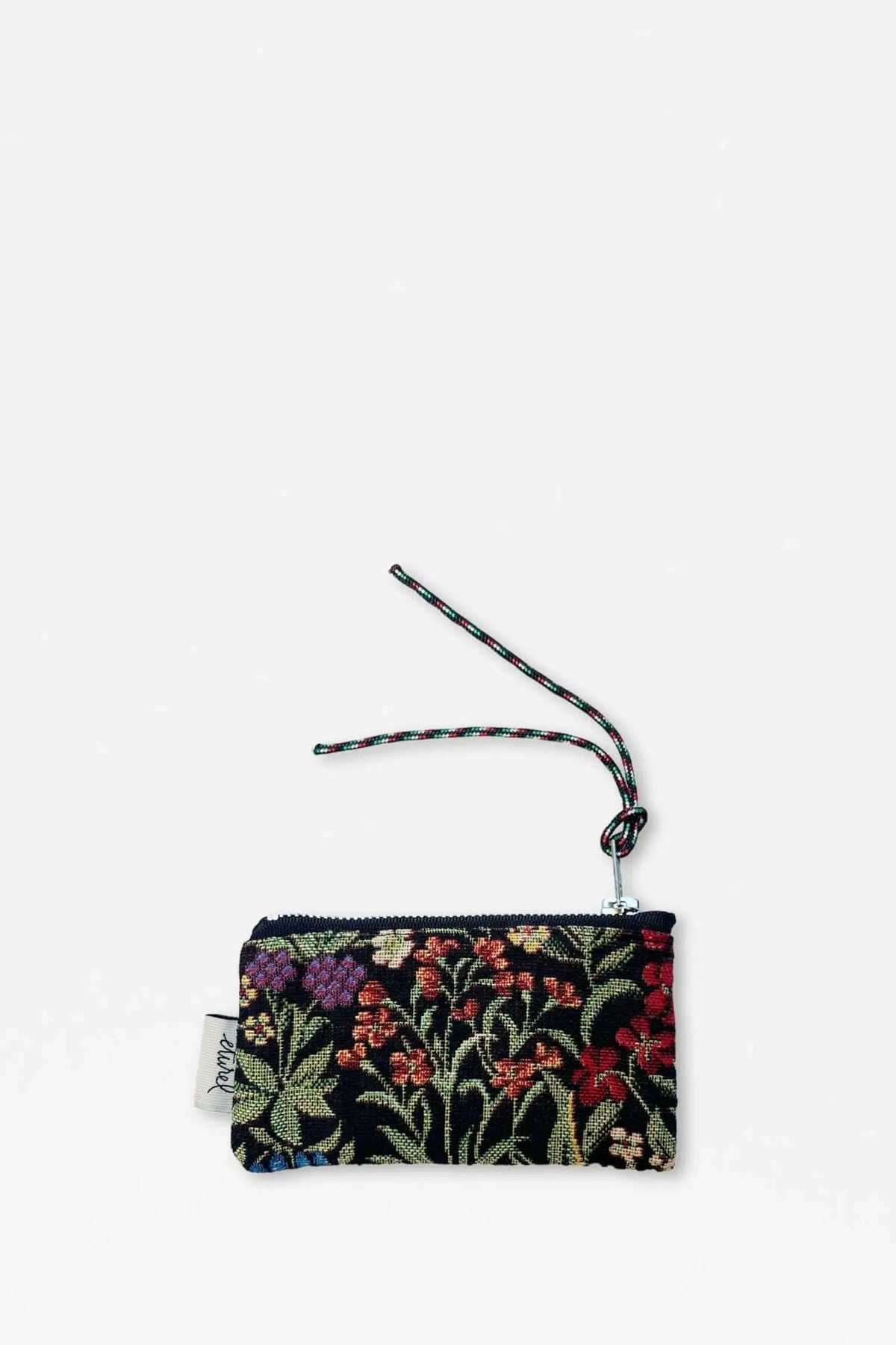 Monedero de tejido jacquard con estampado de flores coloridas sobre fondo negro y cordón decorativo para colgar.
