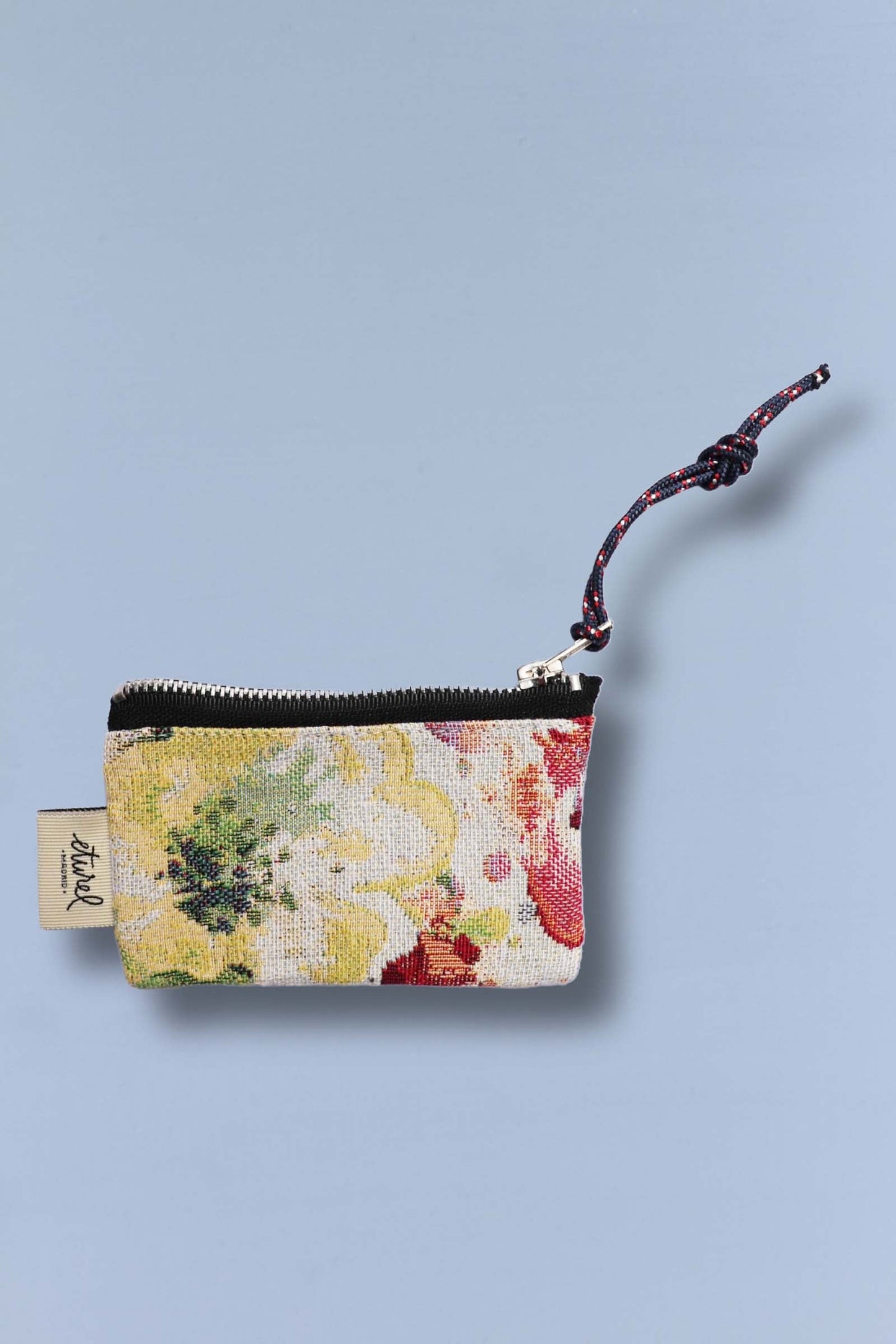 Monedero rectangular de tejido jacquard con estampado de amapolas en tonos amarillos, verdes y rojos, con cierre de cremallera.