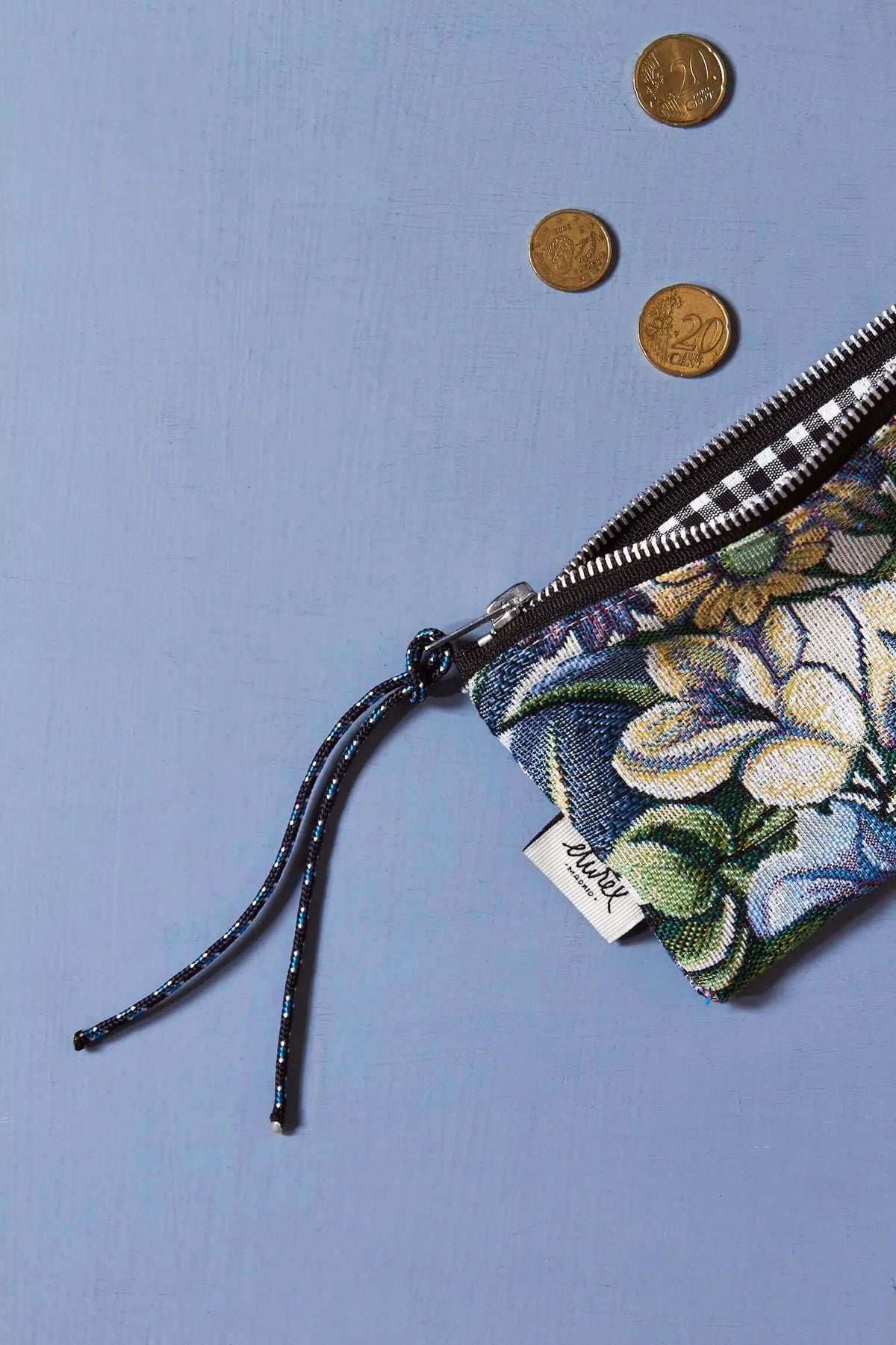 Monedero rectangular de tejido jacquard con estampado de flores azules y hojas verdes, cierre de cremallera y cordón.