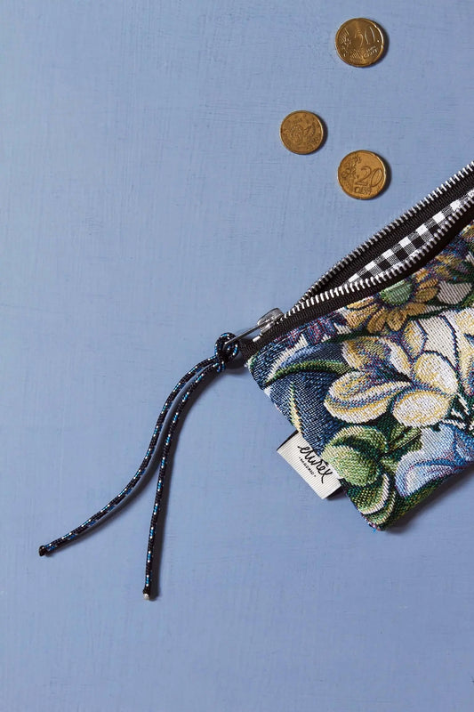 Monedero rectangular de tejido jacquard con estampado de flores azules y hojas verdes, cierre de cremallera y cordón.