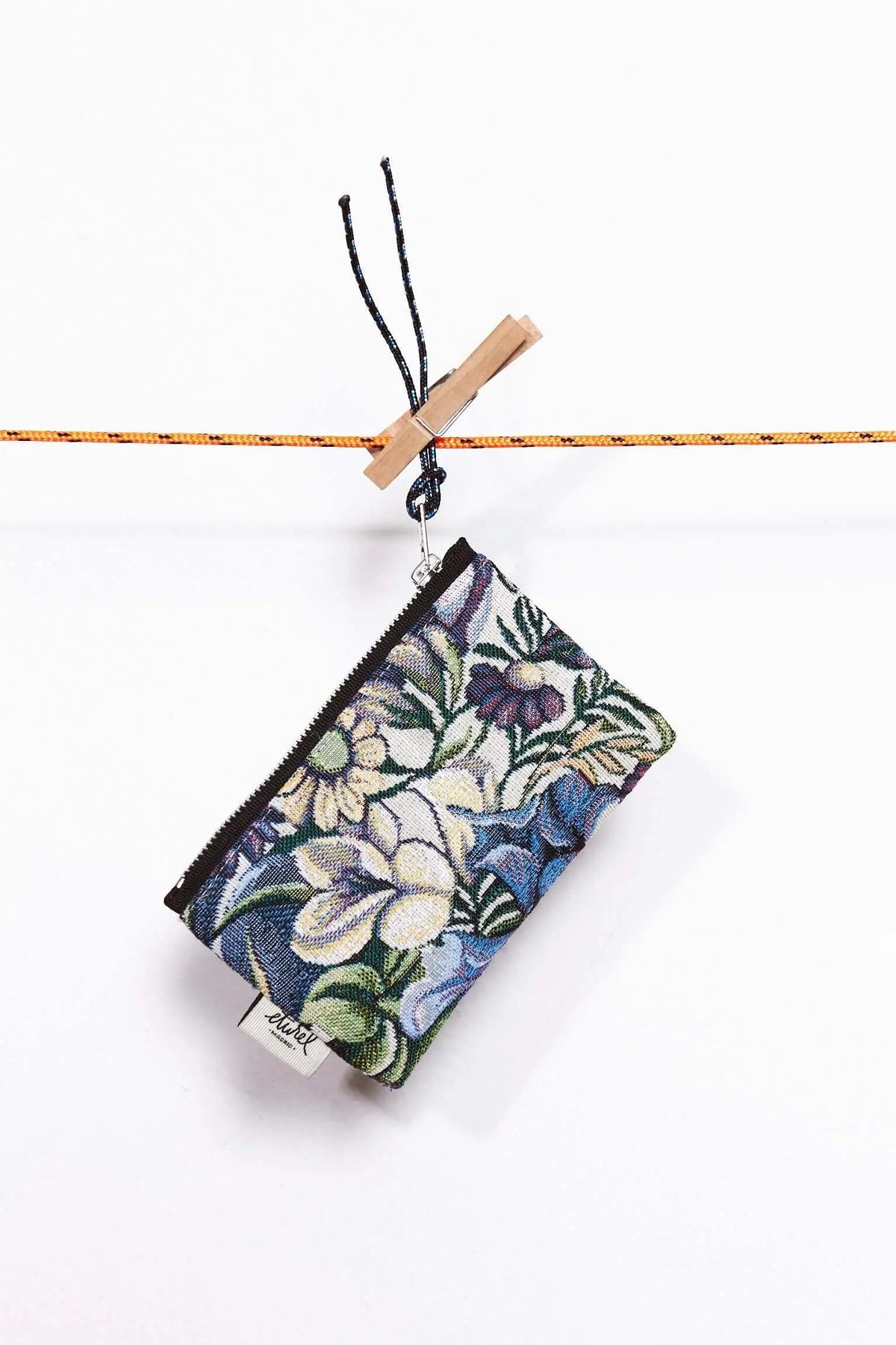 Monedero rectangular de tejido jacquard con estampado de flores y crisantemos azules, colgado con una pinza de madera.