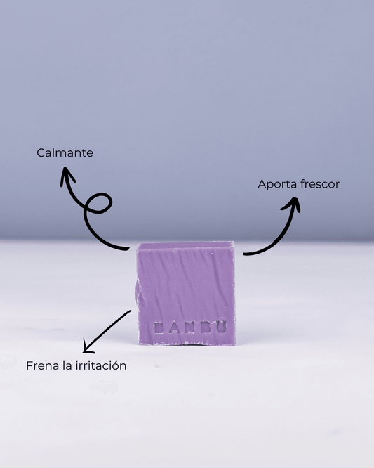 Pastilla de mousse facial lila Banbu con flechas indicando beneficios para piel sensible. Fondo liso, estilo minimalista.