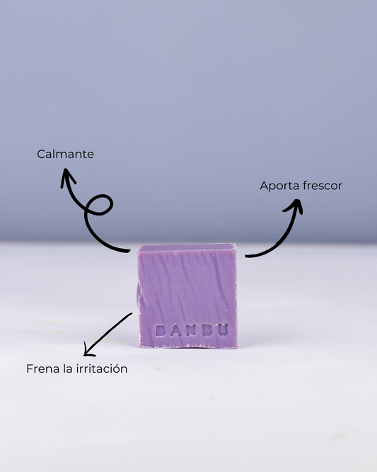 Pastilla de mousse facial lila Banbu con flechas indicando beneficios para piel sensible. Fondo liso, estilo minimalista.