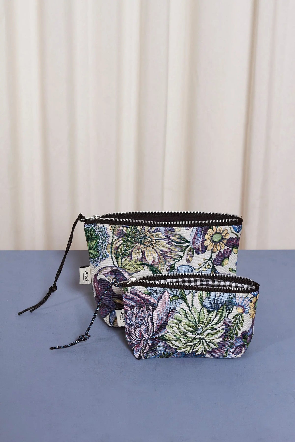 Neceser y estuche de tejido jacquard con estampado floral de crisantemos azules sobre fondo claro y cierre de cremallera.