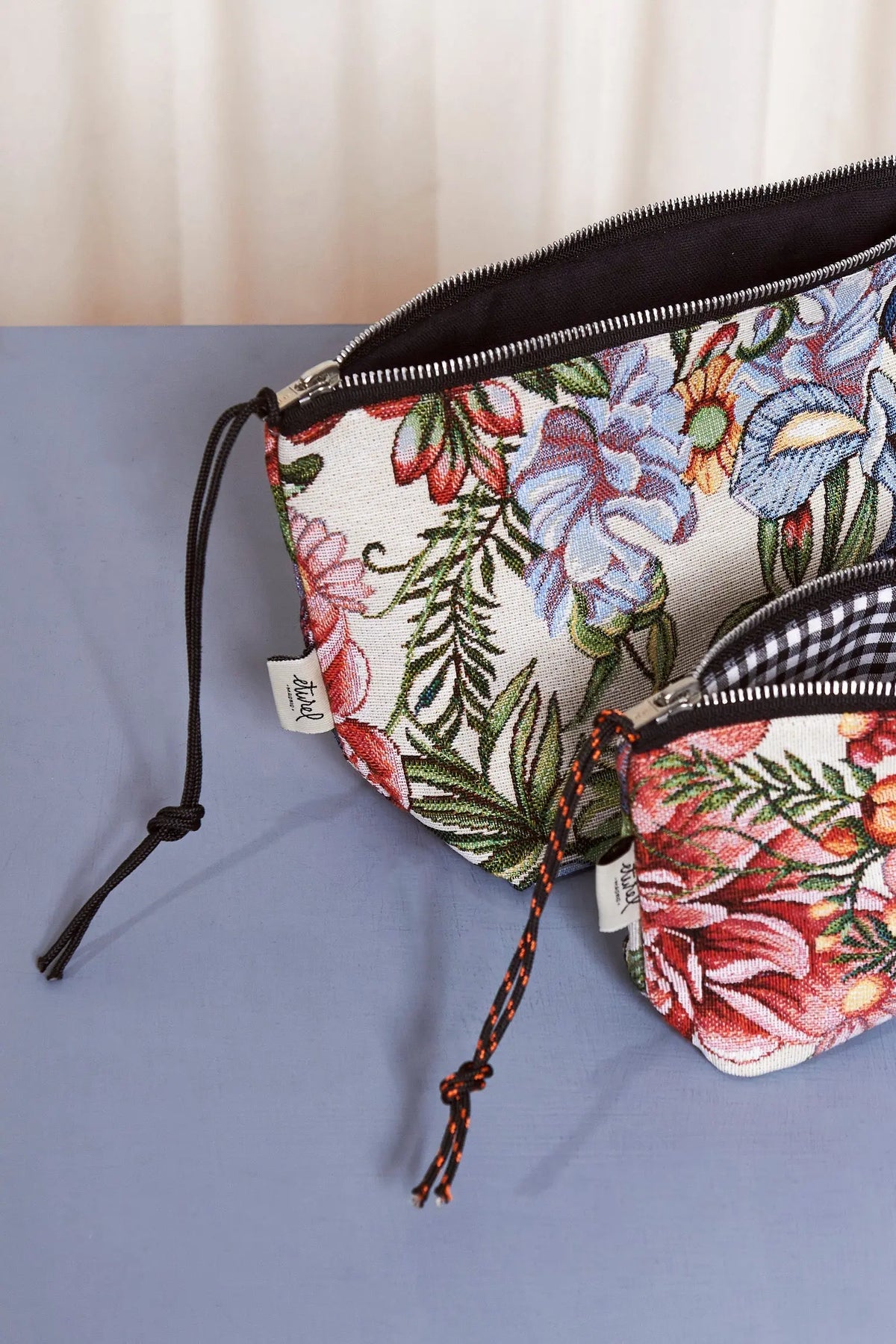 Neceser y estuche de tela jacquard con estampado floral de crisantemos, cremallera metálica y cordón negro.