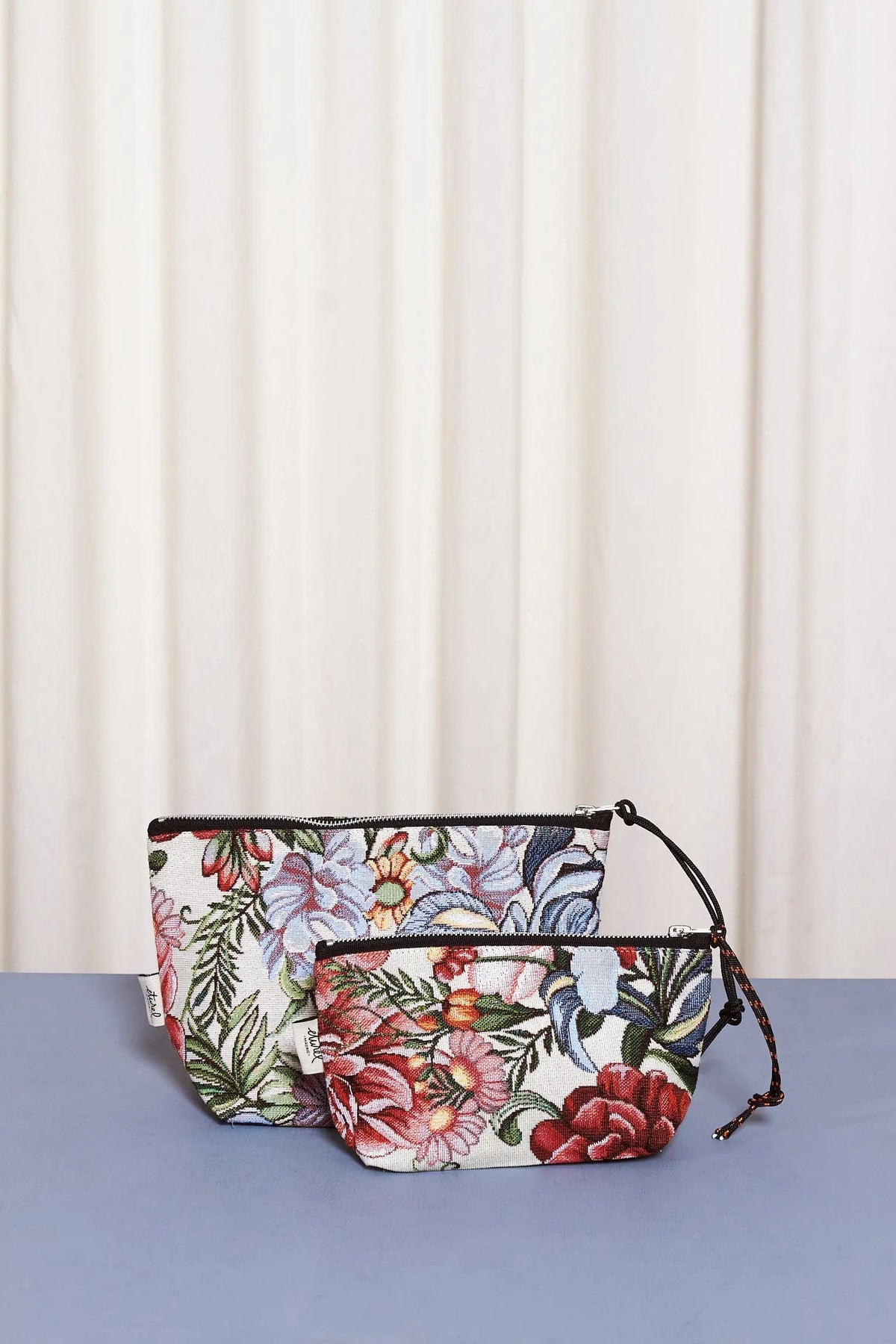 Dos neceseres de tela jacquard con estampado de flores y crisantemos rojos, con cierre de cremallera y tirador de cuerda.
