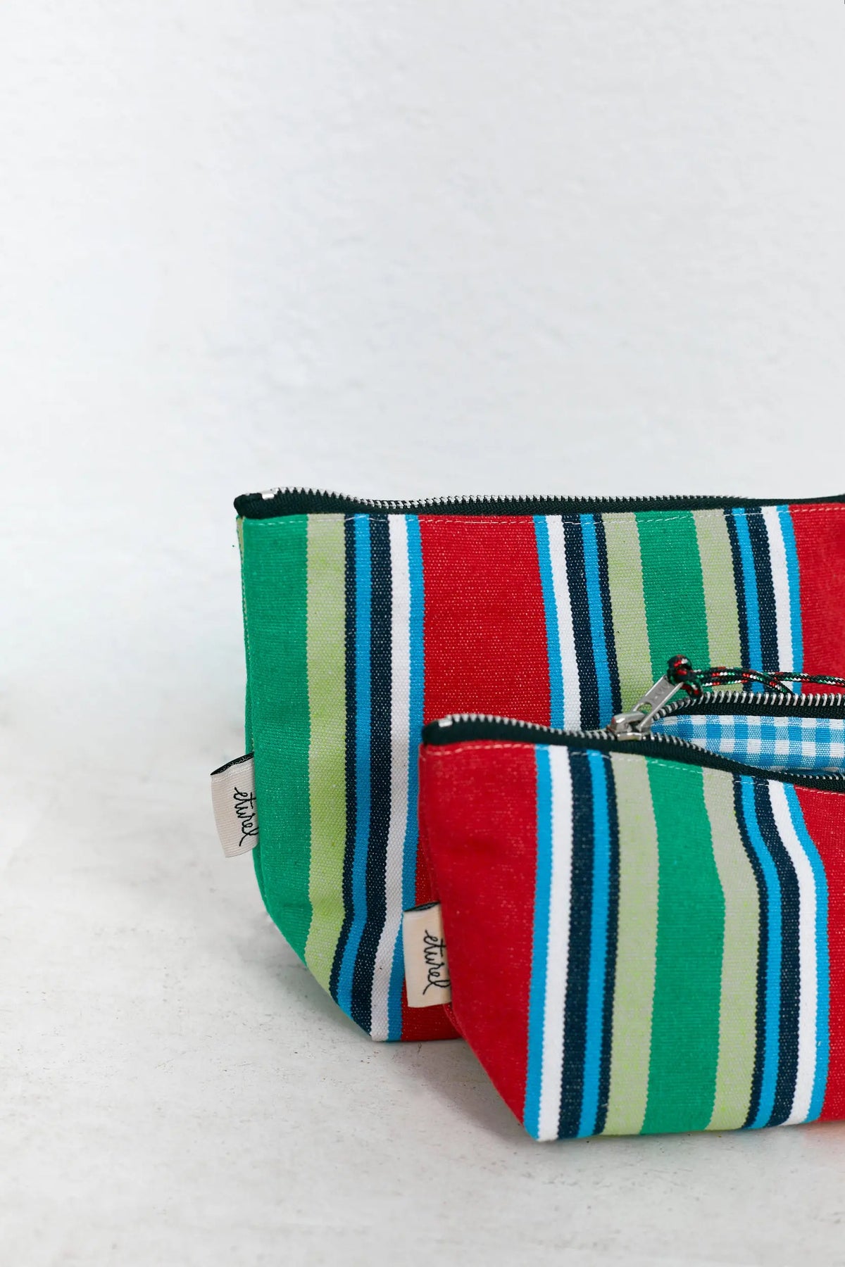 Two zippered canvas pouches with red, green, and blue vertical stripes and a checkered inner lining.