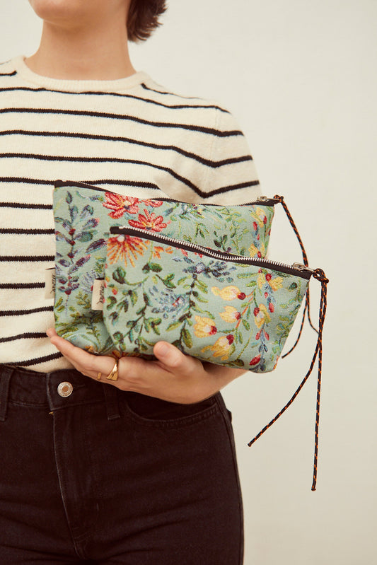 Neceser y estuche de tejido jacquard celeste con estampado de flores coloridas y cremallera con cordón decorativo.