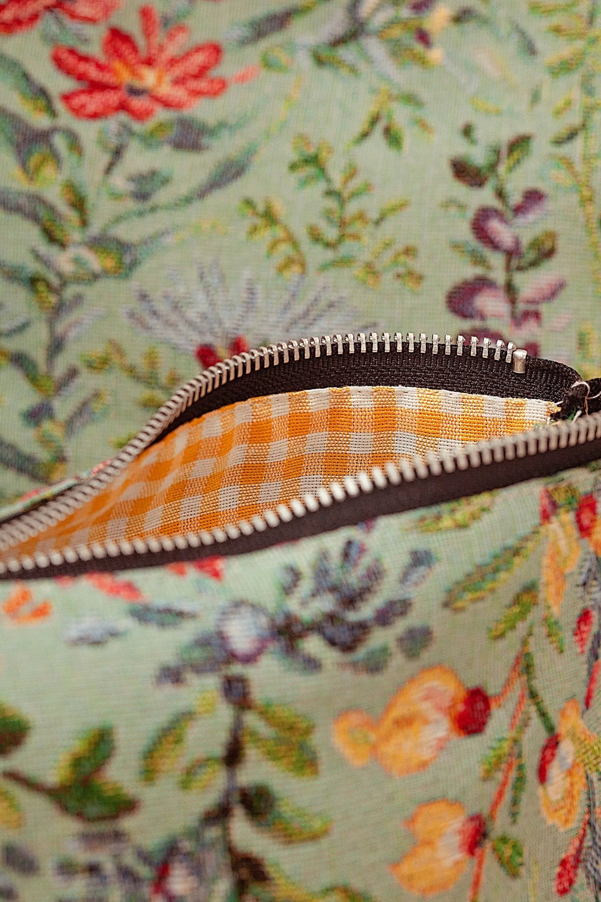 Neceser de tejido jacquard con estampado de azaleas en tonos celeste y forro interior de cuadros vichy amarillos.