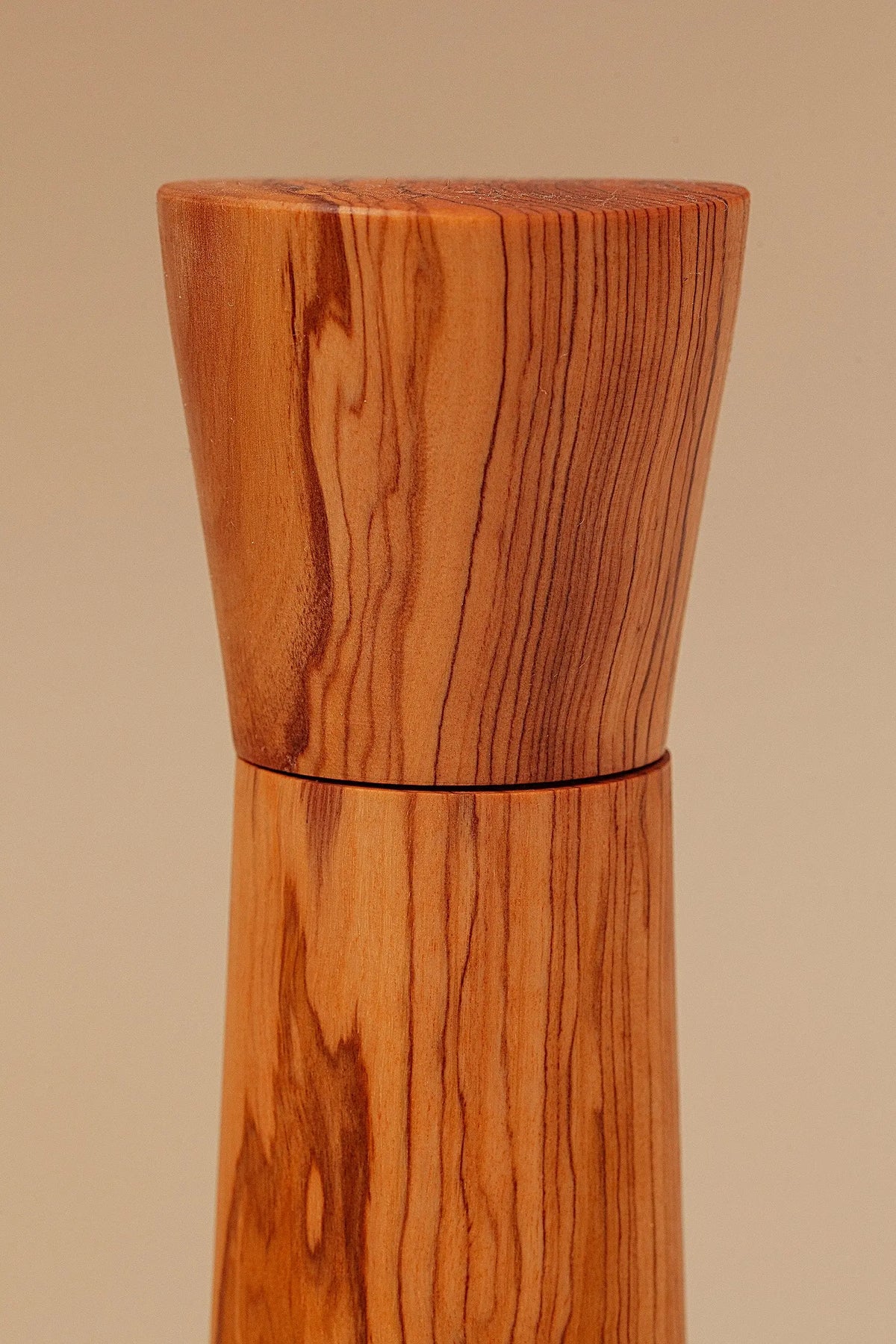 Molinillo de madera de olivo con vetas naturales marcadas, diseño cilíndrico minimalista y acabado cálido artesanal.