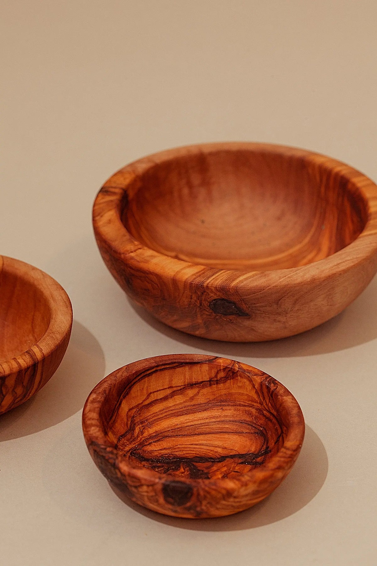 Set de cuencos de madera de olivo con veteado natural, acabado artesanal y tonos marrones sobre fondo neutro.