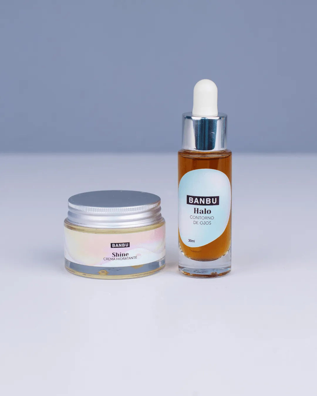 Pack facial Banbu: crema hidratante en tarro de cristal y contorno de ojos en frasco con gotero sobre fondo gris.