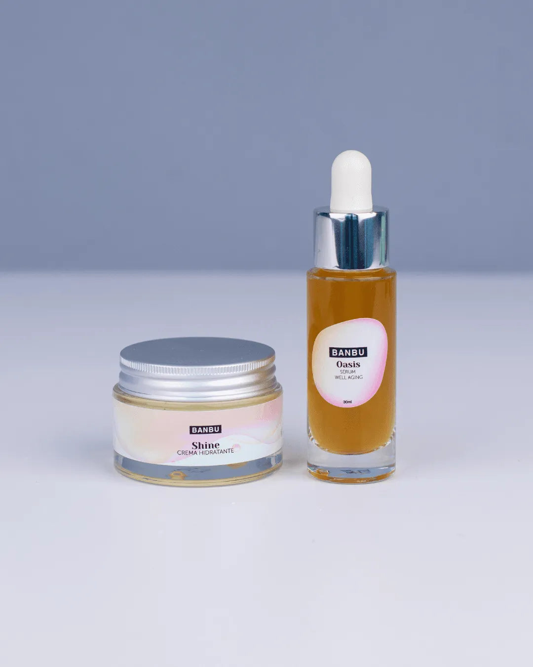 Pack rutina facial Banbu: tarro de crema y frasco de sérum con cuentagotas, sobre fondo gris. Estética limpia y natural.