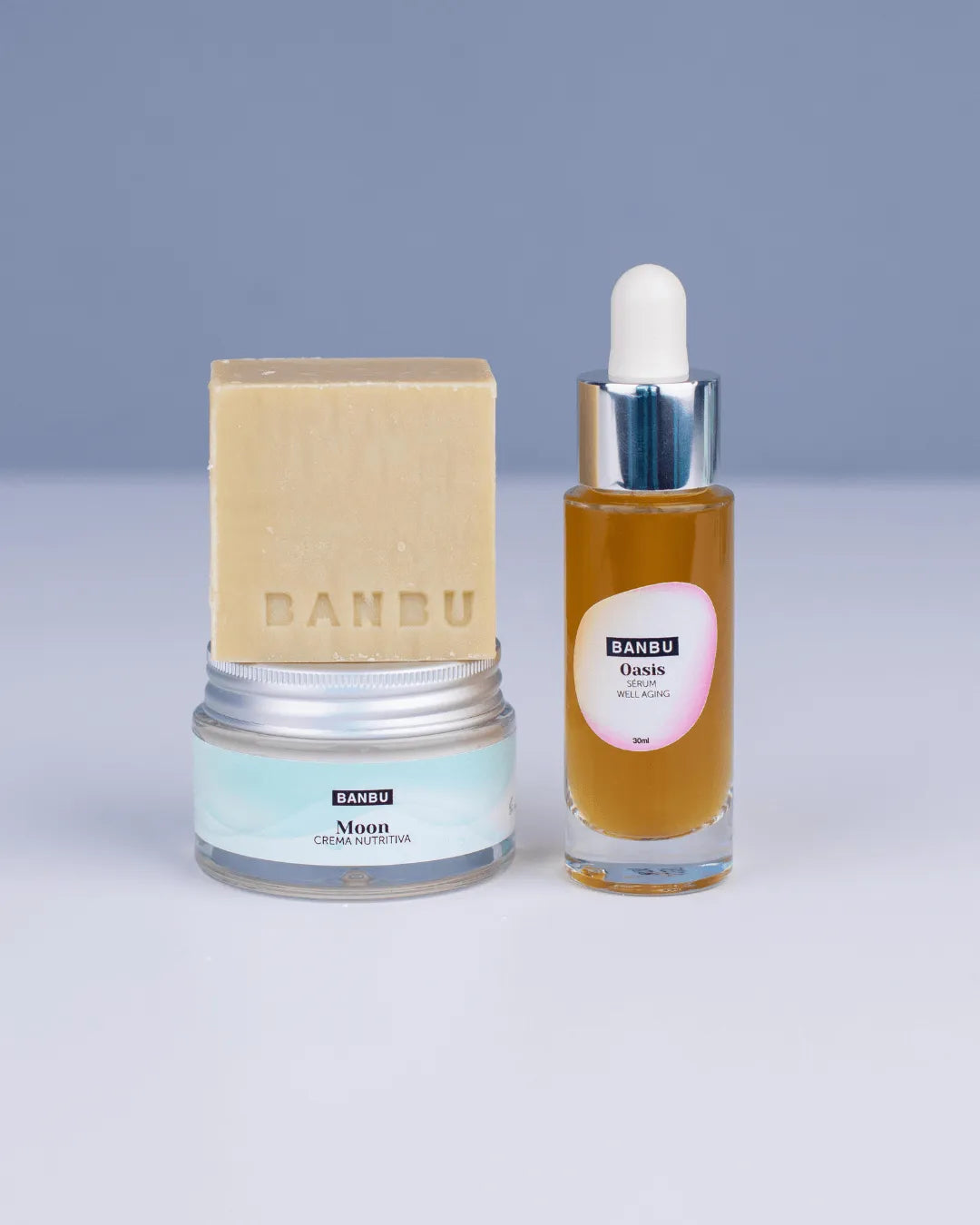 Pack facial Banbu: pastilla de jabón beige, tarro de crema azulado y sérum dorado en frasco de cristal con gotero.