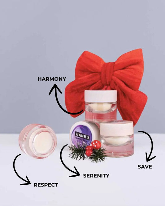 Pack de tres perfumes sólidos Banbu en tarritos de cristal con tapa de madera, lazo rojo y adornos navideños.