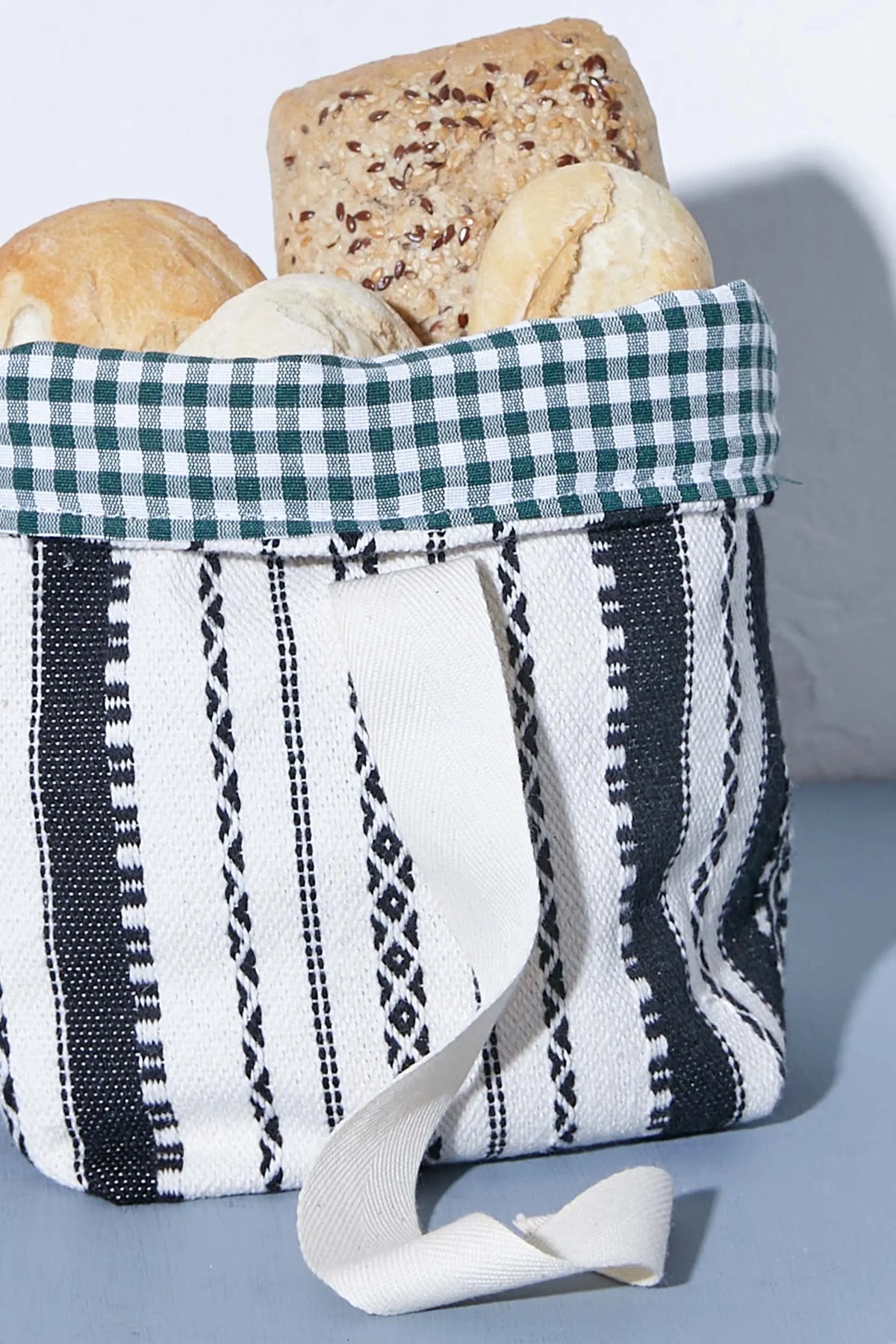 Small fabric bread basket with black-and-white striped design and a green-and-white checkered interior rim.