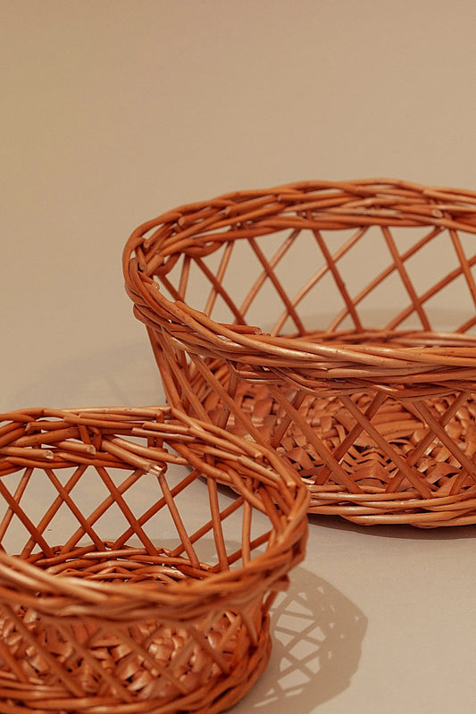Set de dos paneras de mimbre natural con diseño calado, estilo artesanal en color marrón cálido y acabado trenzado.