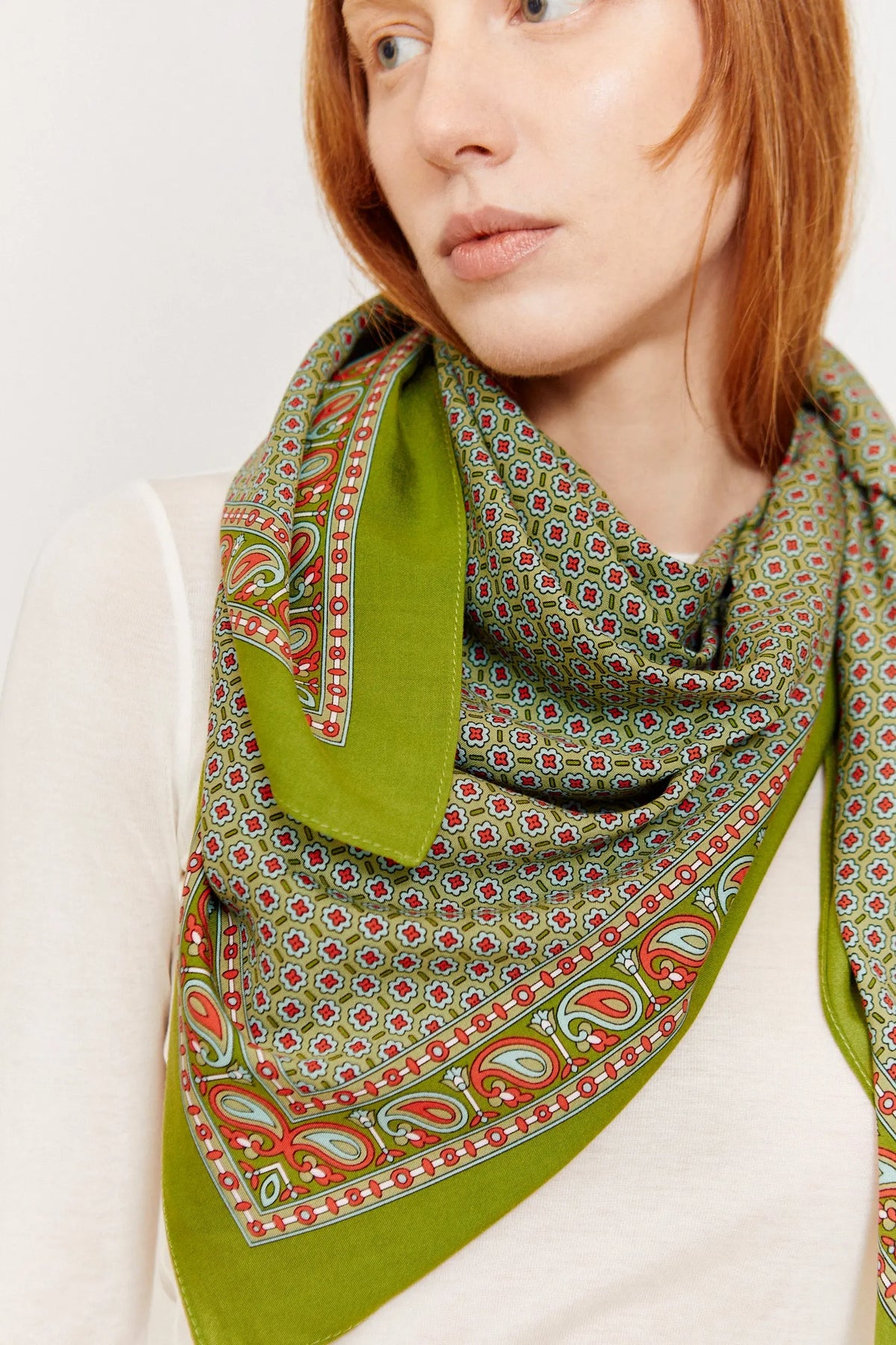 Pañuelo aragonés verde con estampado de flores pequeñas y cenefa de estilo paisley en tonos rojos y azul claro.