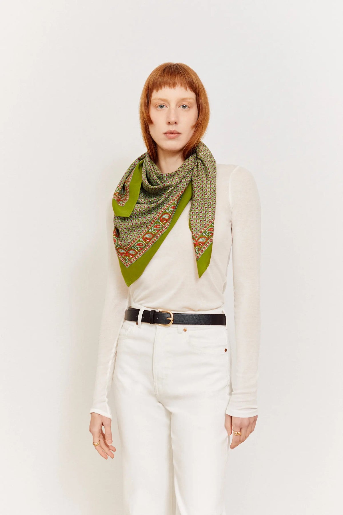Modelo con pañuelo aragonés verde de tejido ligero, estampado geométrico y cenefa clásica sobre fondo blanco.