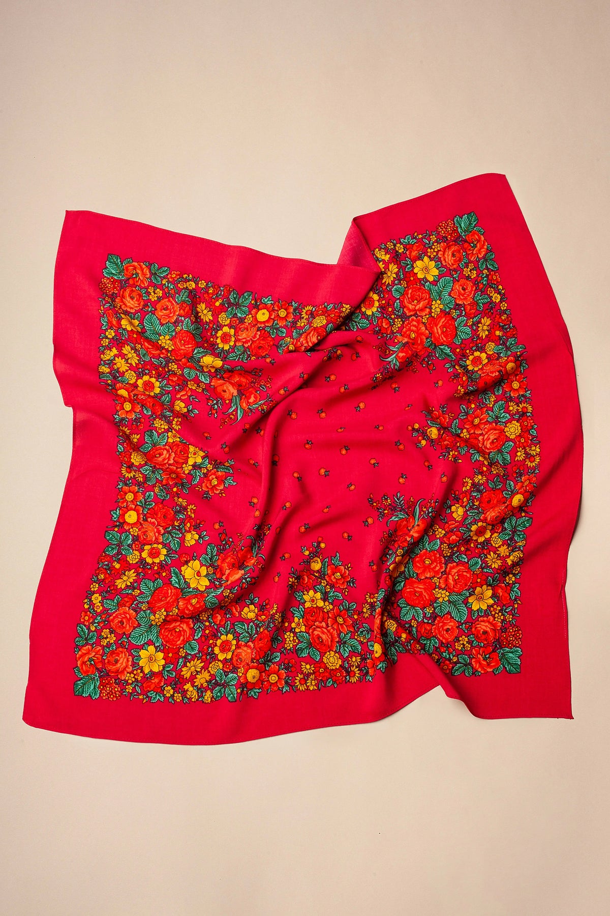 Pañuelo cuadrado de color rosa intenso con estampado de flores tradicionales en tonos rojos, amarillos y hojas verdes.