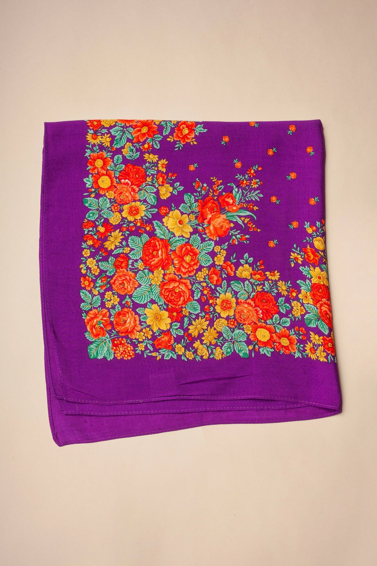 Square purple scarf with a vibrant floral pattern featuring red and yellow roses, green leaves, and small flower buds.