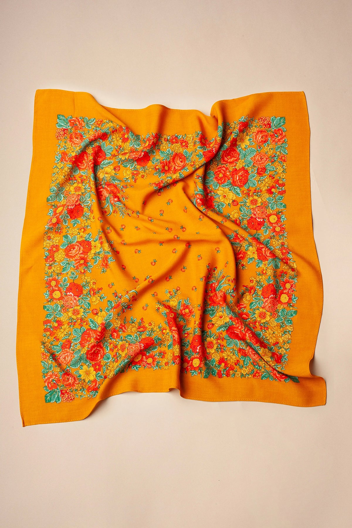 Ochre square scarf with a vibrant floral border featuring red roses, yellow flowers, and green leaves.