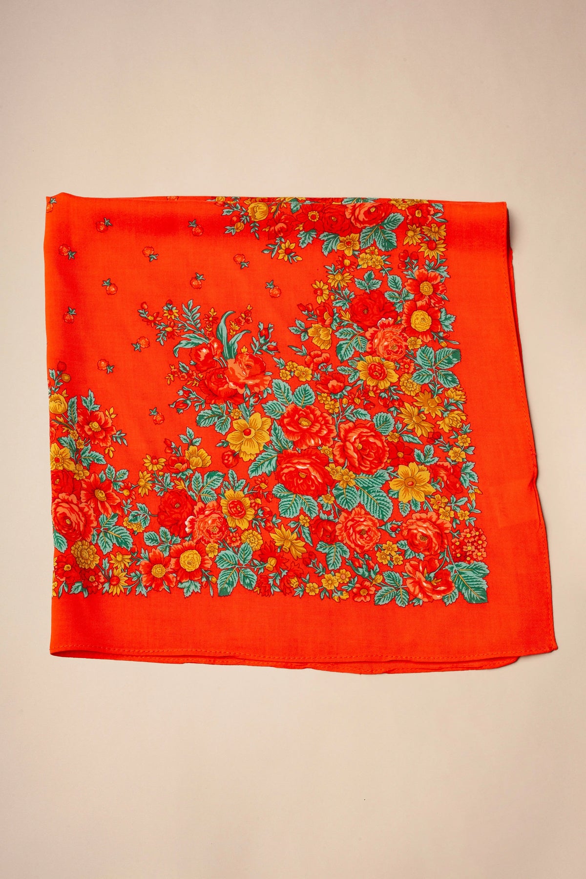 Red square scarf with a traditional floral print in orange, yellow, and green, featuring detailed rose patterns.
