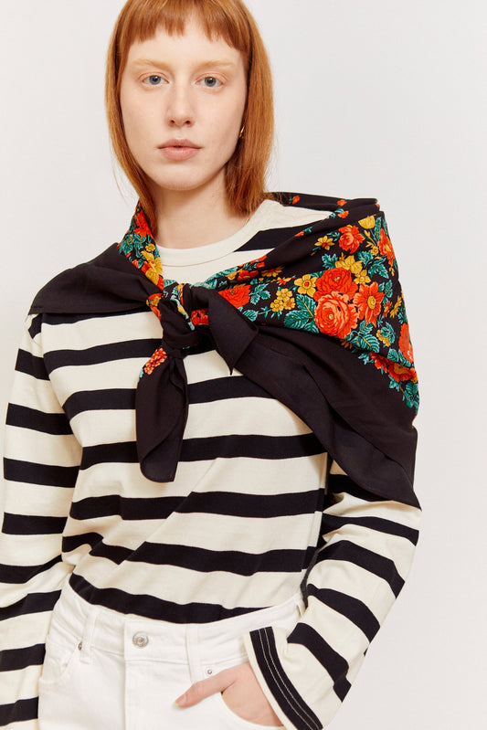 Pañuelo negro con estampado floral colorido, estilo tradicional portugués, anudado al cuello sobre camiseta a rayas.
