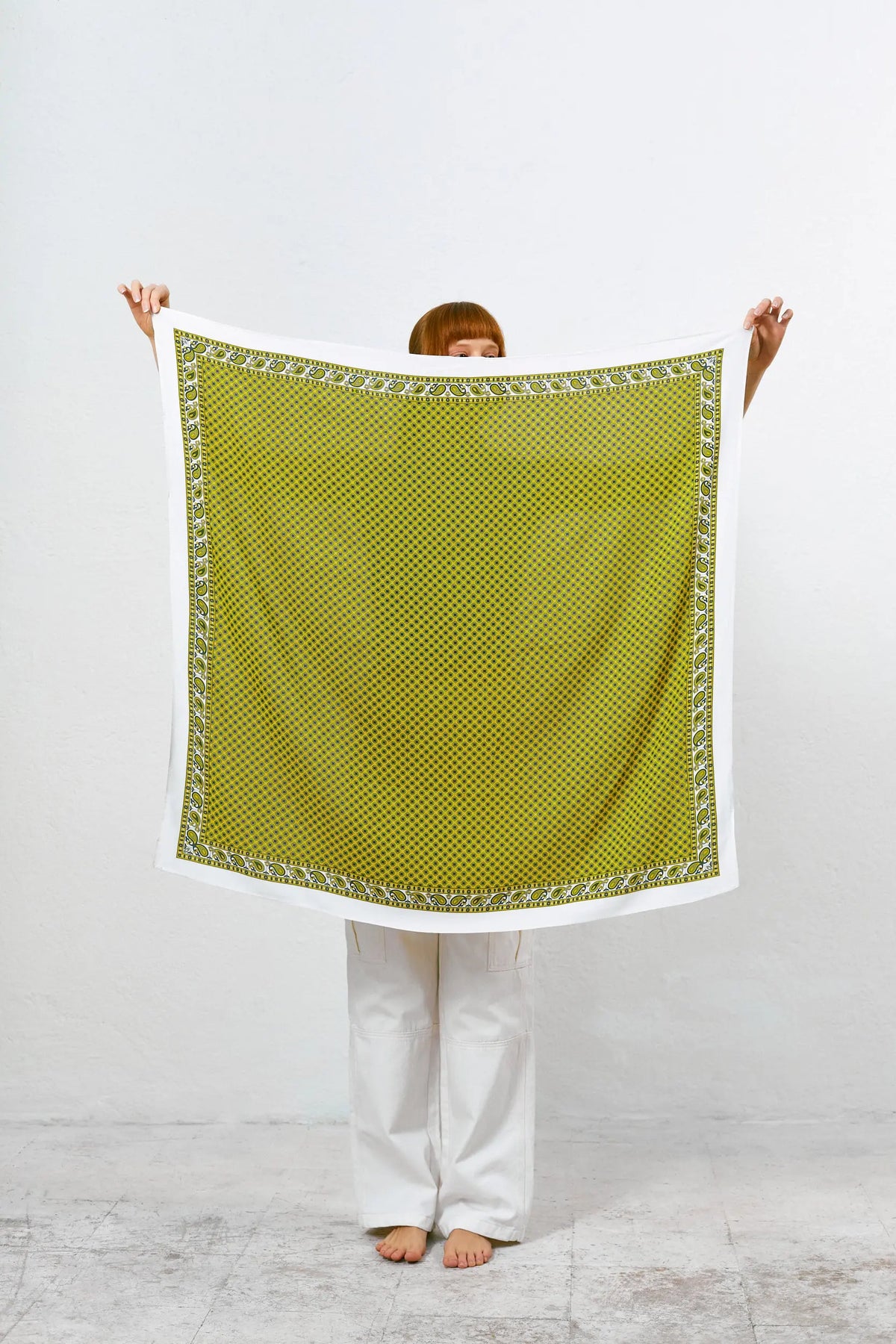 Pañuelo aragonés cuadrado, estampado geométrico y cenefa paisley en tonos ocre y verde sobre fondo blanco.