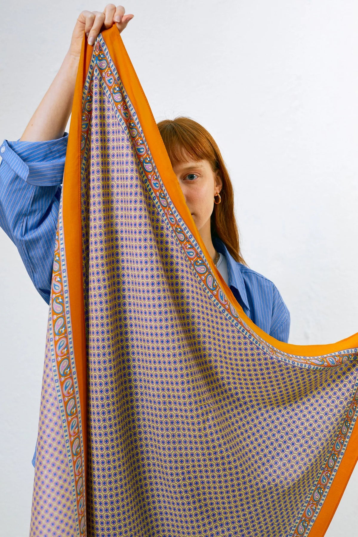 Pañuelo con estampado geométrico azul y bordes anchos en tono anaranjado con detalles de motivos vegetales.