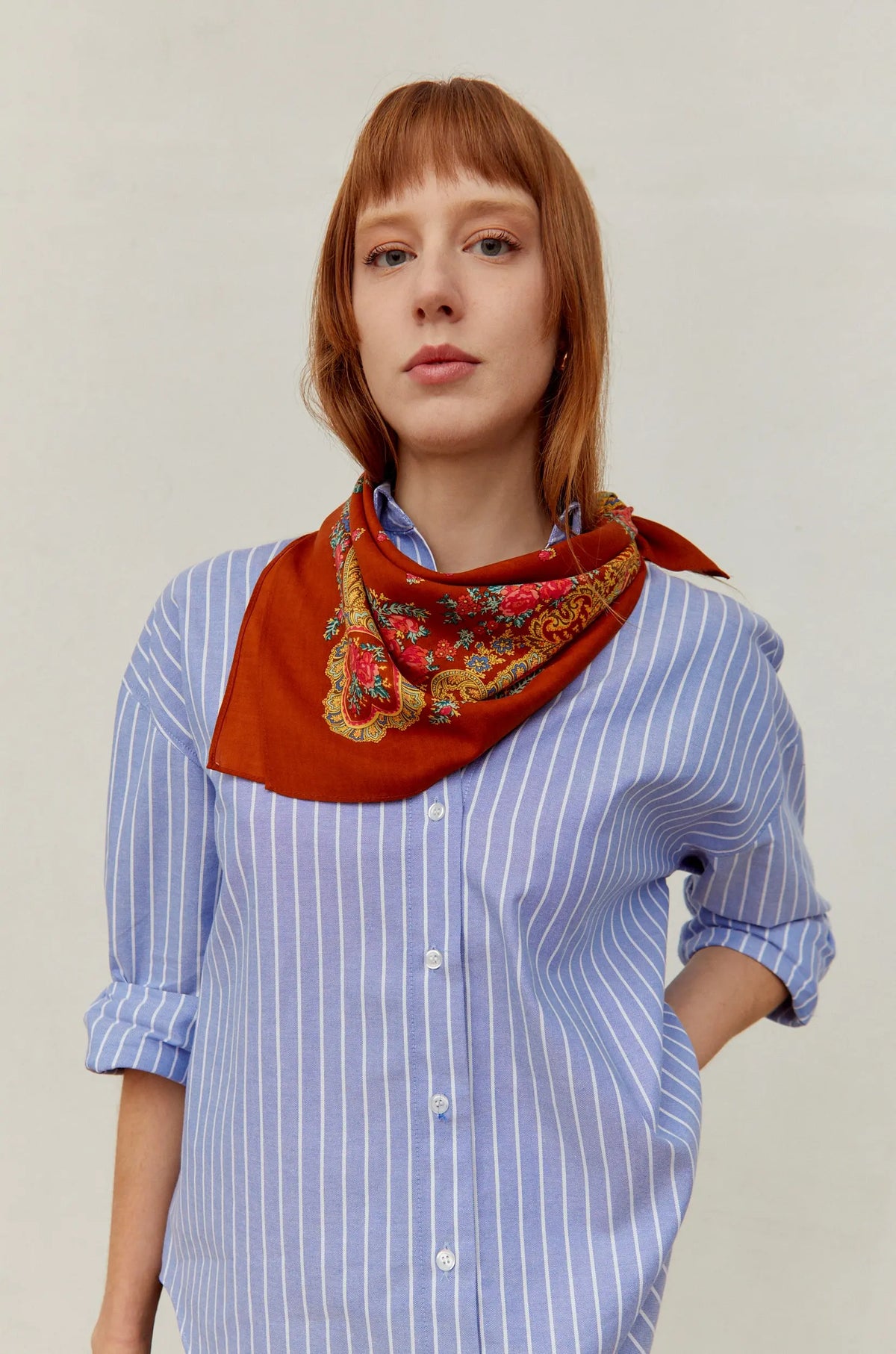 Pañuelo de estilo tradicional portugués color caldero con estampado floral y cadenas, anudado al cuello.