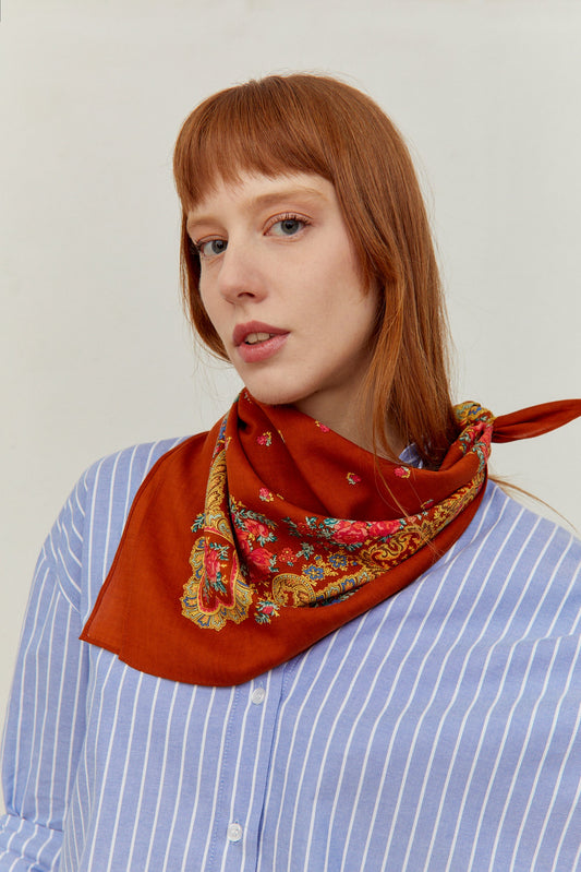 Pañuelo color caldero con estampado floral tradicional portugués y detalles de cadenas anudado al cuello.