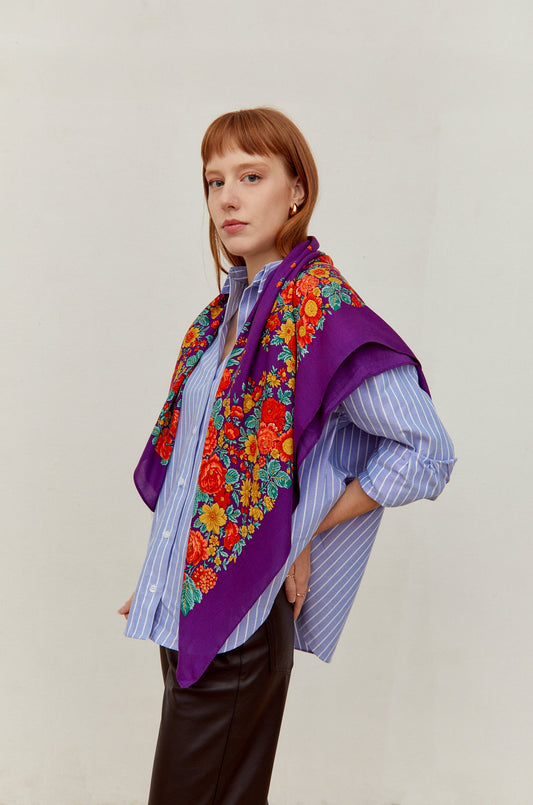 Pañuelo morado de estilo tradicional con estampado de flores coloridas en tonos rojos y amarillos sobre hombros.
