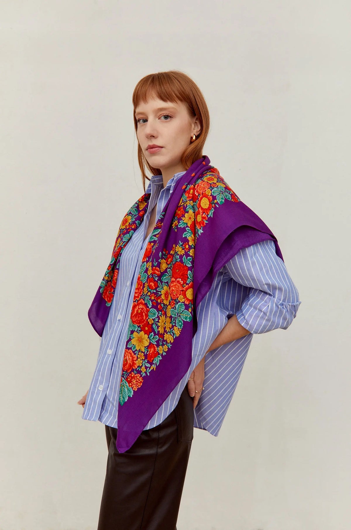 Pañuelo morado de estilo tradicional con estampado de flores coloridas en tonos rojos y amarillos sobre hombros.