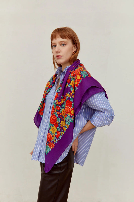 Pañuelo morado de estilo tradicional con estampado de flores coloridas en tonos rojos y amarillos sobre hombros.