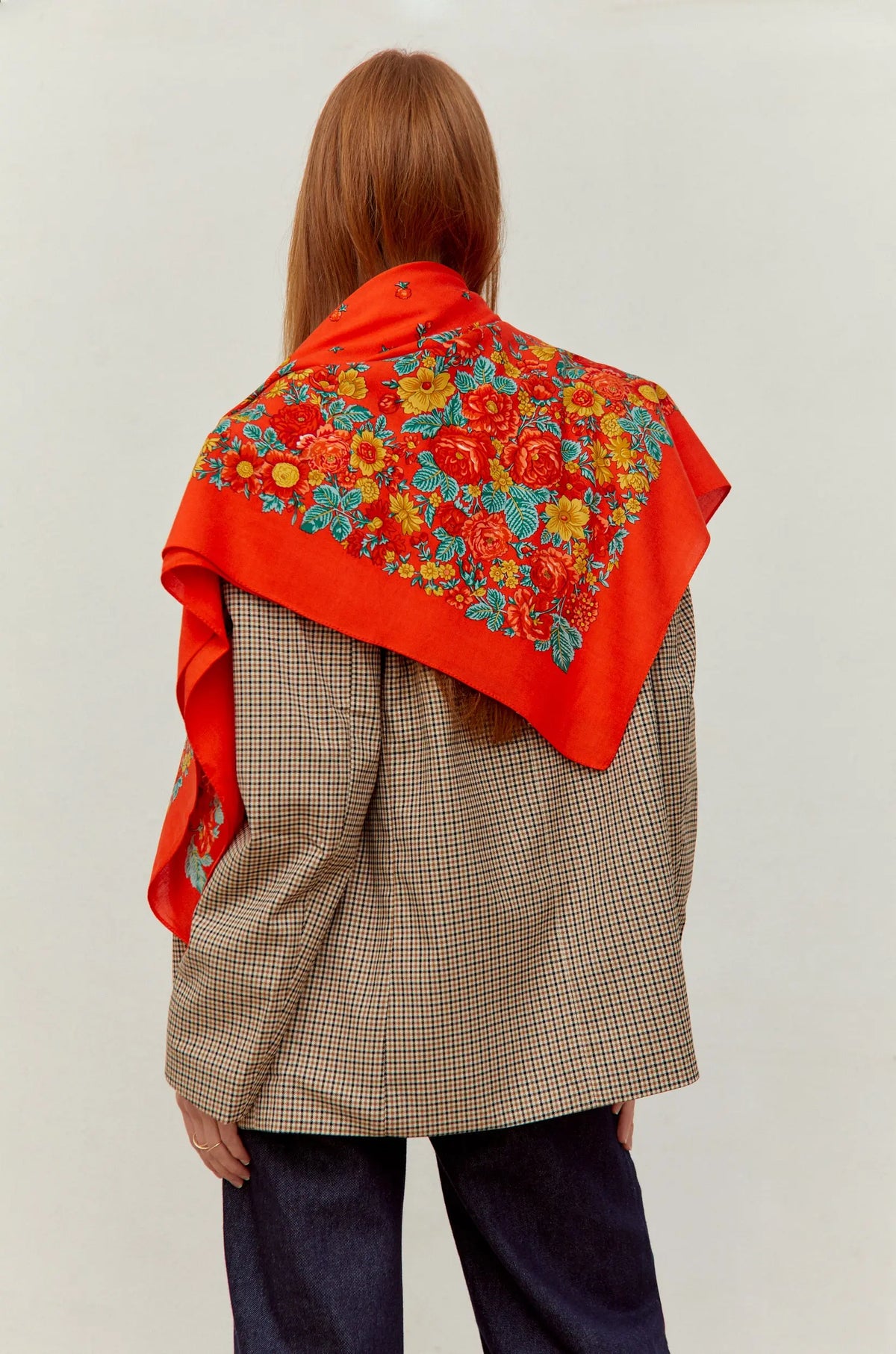 Pañuelo rojo con estampado floral tradicional, diseño cuadrado, estilo artesanal sobre chaqueta de cuadros.