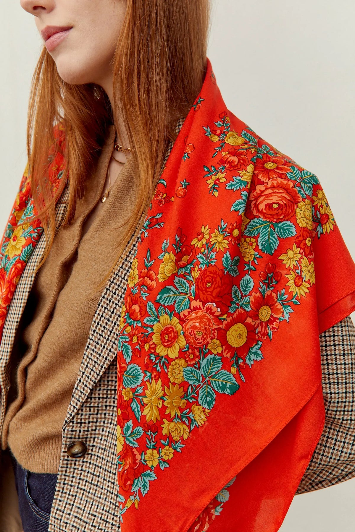 Pañuelo rojo de estilo portugués con estampado de flores coloridas, hojas verdes y acabado satinado sobre los hombros.