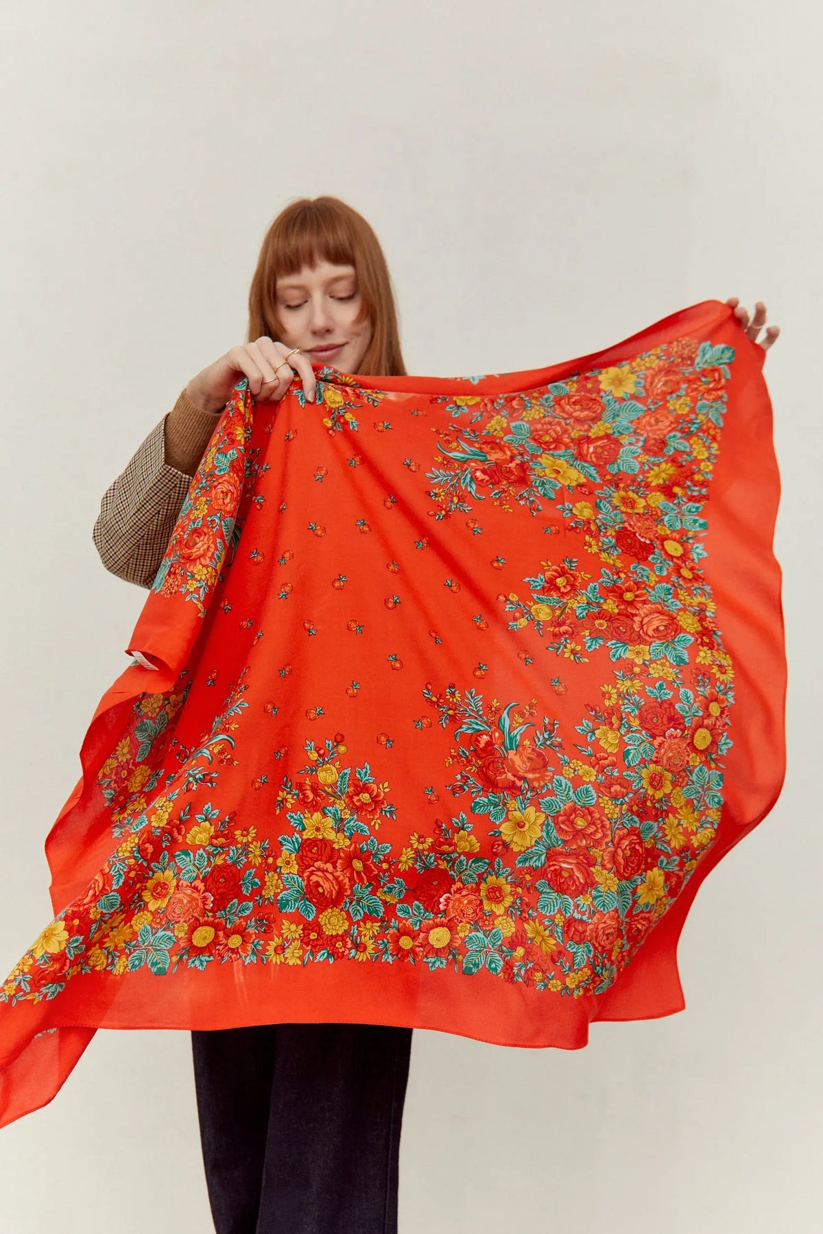 Pañuelo rojo de estilo tradicional con estampado de flores coloridas y follaje verde, tejido ligero y elegante.