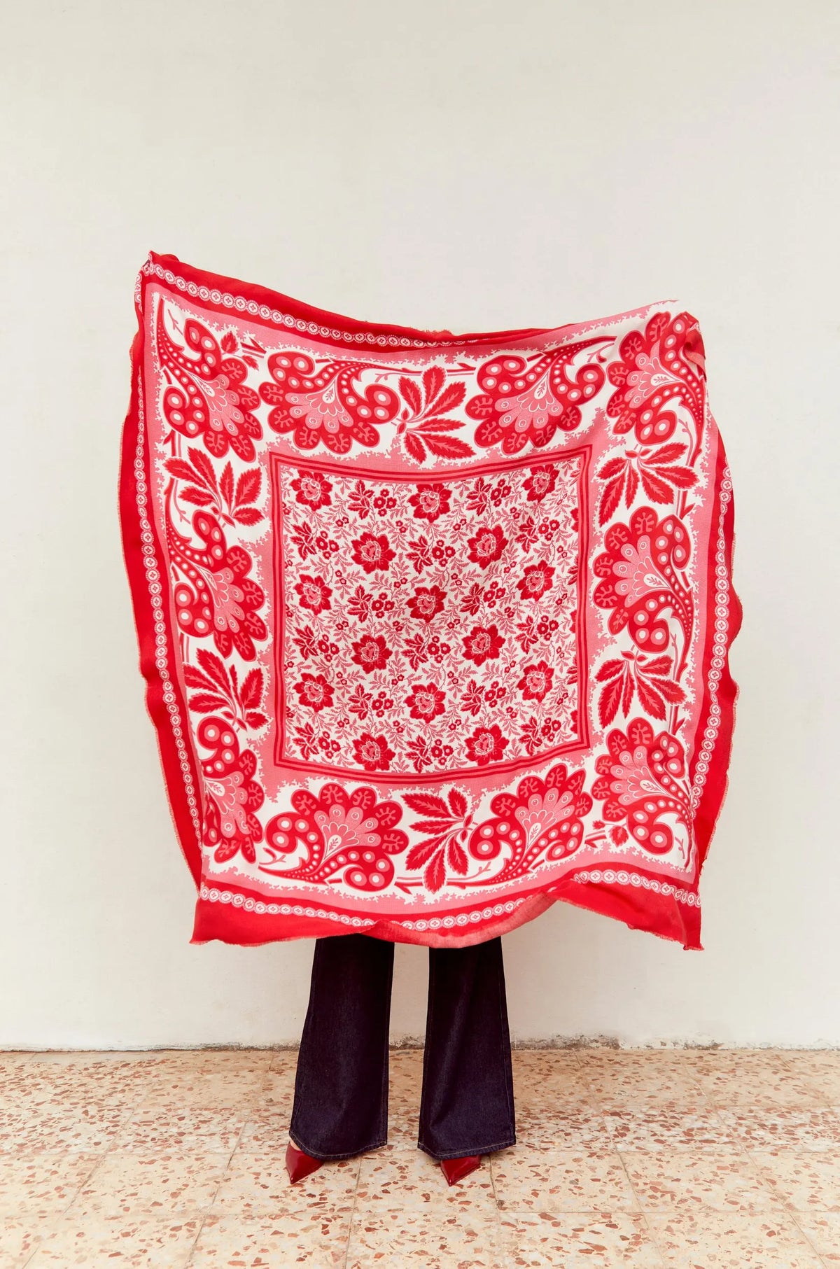 Pañuelo cuadrado de tela ligera con estampado floral y de cachemir en tonos rojo, rosa y blanco sobre fondo claro.