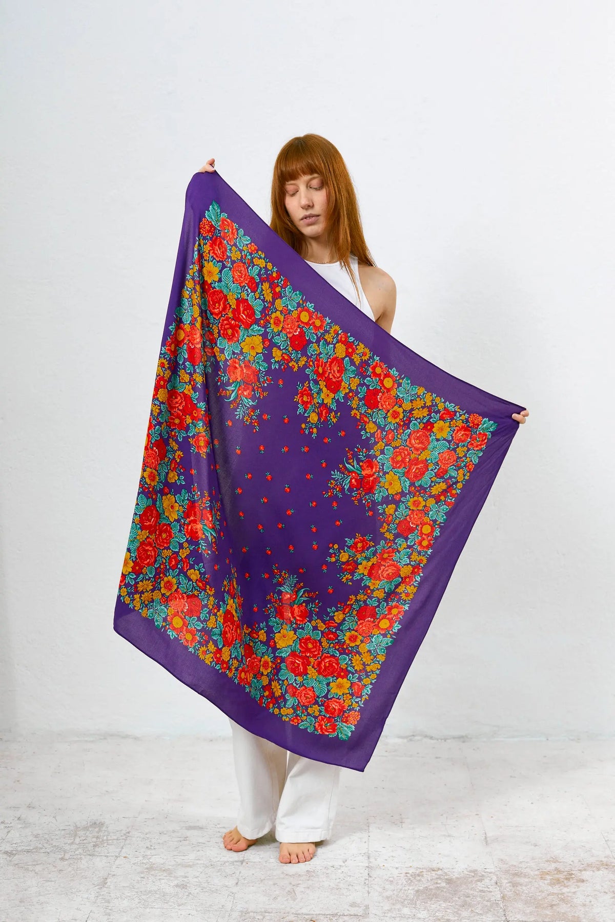 Pañuelo cuadrado de tela morada con estampado floral tradicional de flores rojas, amarillas y verdes.