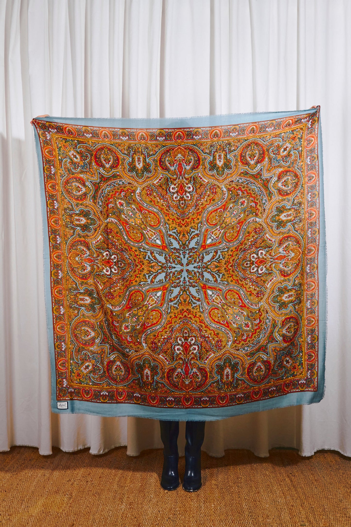 Pañuelo de lana azul con estampado paisley multicolor en tonos naranjas, rojos y amarillos, de estilo clásico.
