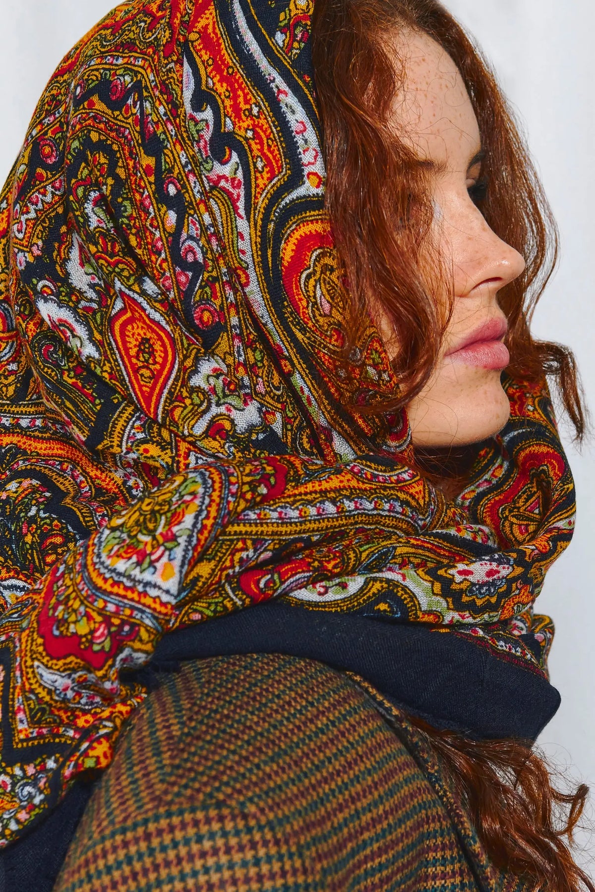 Pañuelo de lana negro con estampado paisley multicolor y flores sobre fondo oscuro, estilo tradicional elegante.