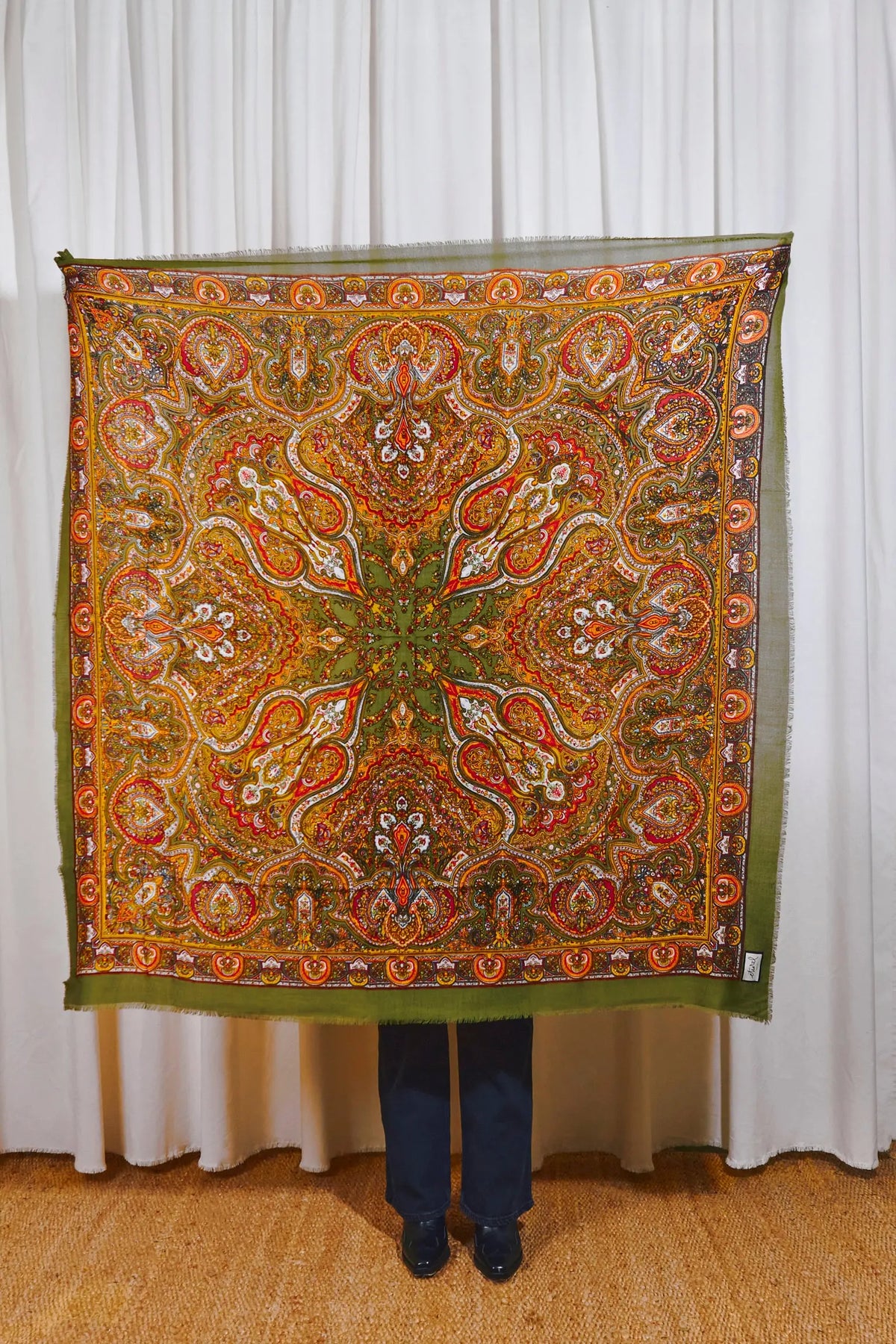 Pañuelo cuadrado de lana verde oliva con estampado paisley multicolor detallado y bordes desflecados.