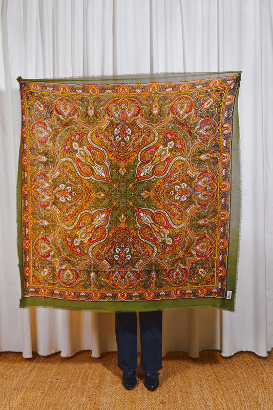 Pañuelo cuadrado de lana verde oliva con estampado paisley multicolor detallado y bordes desflecados.